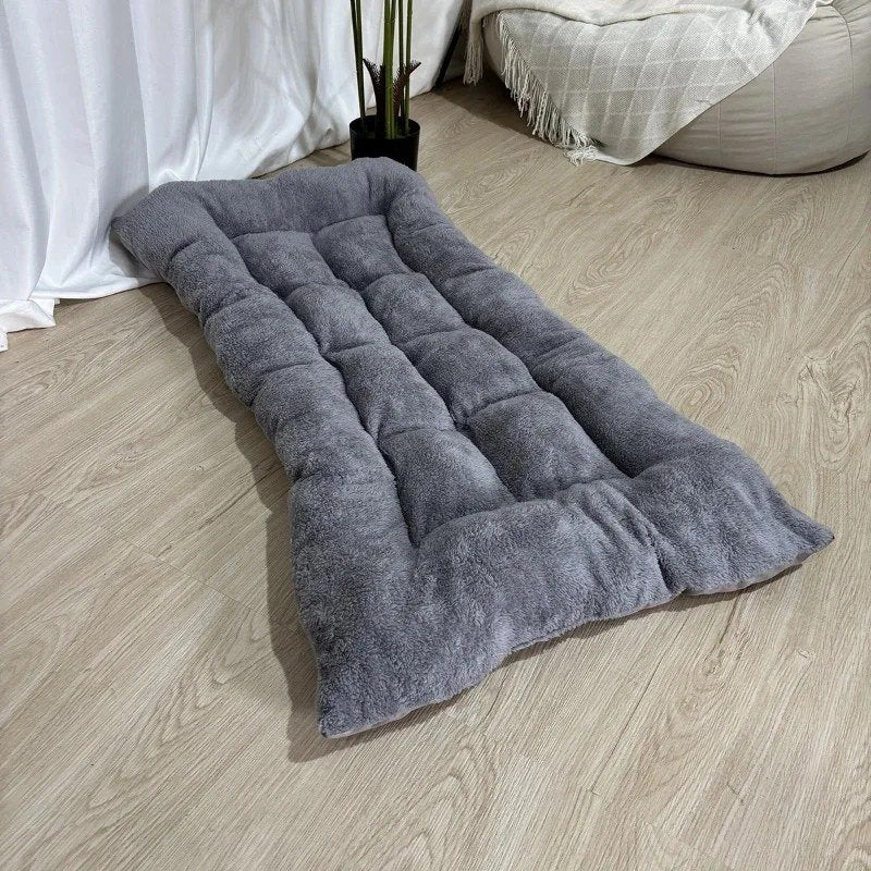 Grey quilted plush dog bed mat on a wooden floor